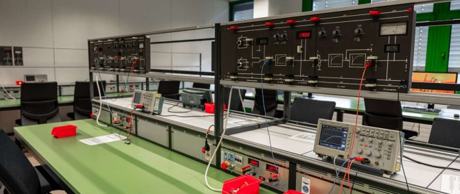 Auf dem Bild sind im Labor verschiedene Laborgeräte und sonstige Ausstattung zu sehen, wie zum Beispiel Monitore, Oszilloskope und Messgeräte.