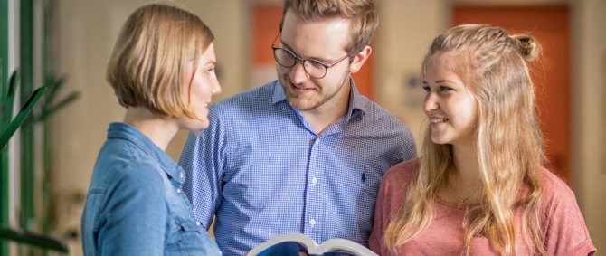 Zwei junge Frauen und ein junger Mann unterhalten sich miteinander.