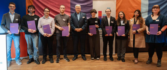 Eine Gruppe von jungen Menschen mit Urkunden in der Hand lächelt in die Kamera.