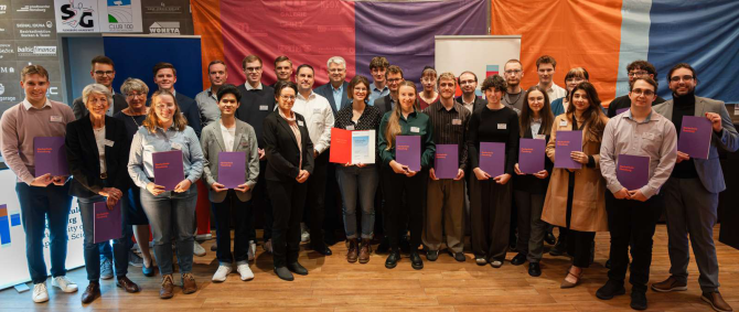 Eine große Gruppe junger Menschen mit Urkunden in der Hand, lächelt in die Kamera.