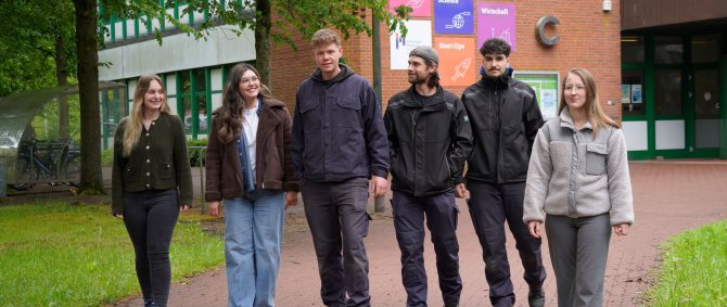 Eine Gruppe mit Menschen auf dem grünen Campus.