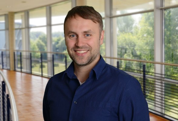 Porträtfoto: Malte Fritz im audimax. Er trägt kurze Haare, einen Dreitagebart und ein dunkelblaues Hemd.