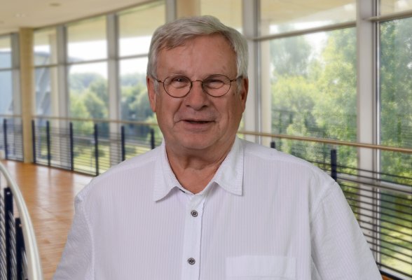 Porträtfoto: Klaus-Michael Heinze im audimax, er trägt die grauen Haaare kurz, eine Brille und ein weißes Hemd.