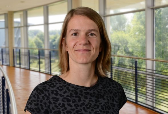 Porträtfoto: Regina Mielke im audimax, sie trägt die schulterlangen, dunklblonden Haare offen und ein grau-schwarz gemustertes Oberteil.