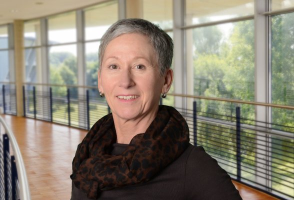 Porträtfoto: Andrea Jaspersen im audimax, sie trägt kurze, graue Haare, ein dunkles Oberteil und einen Schal mit Leoparden-Print.
