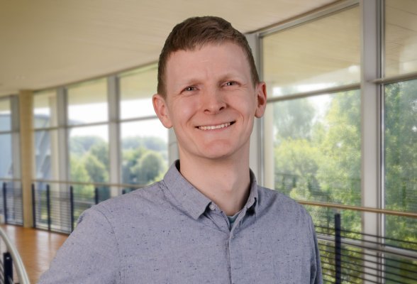 Porträtfoto: Bertin Freese im audimax, er trägt dunkelblonde, kurze Haaare und ein hellblaues Hemd.