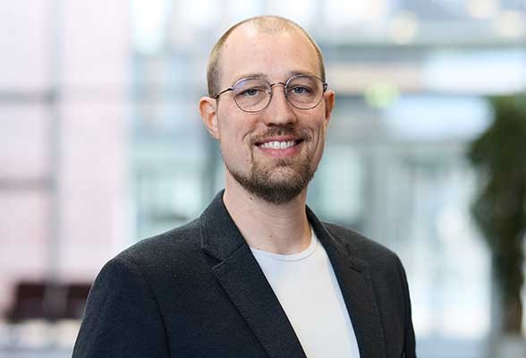 Portraitfoto von Torben Terwey mit Brille, weißem T-Shirt und schwarzem Sakko.