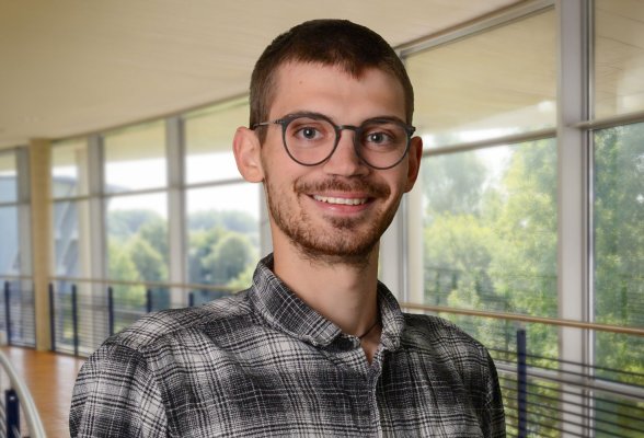 Portraitfoto: Felix Lehmann im audimax, er trägt Brille und einen leichten Bart; sein Hemd ist grau-schwarz kariert.