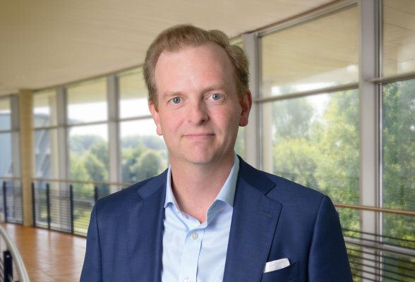 Porträtfoto: Manuel Moritz im audimax, er trägt blonde, kurze Haare und ein dunkelblaues Jackett über dem hellblauen Hemd.