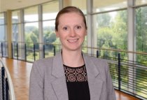 Porträtfoto: Marina Blohm im audimax, sie trägt die Harre zusammengebunden und einen grauen Blazer über einem schwarzen Oberteil.