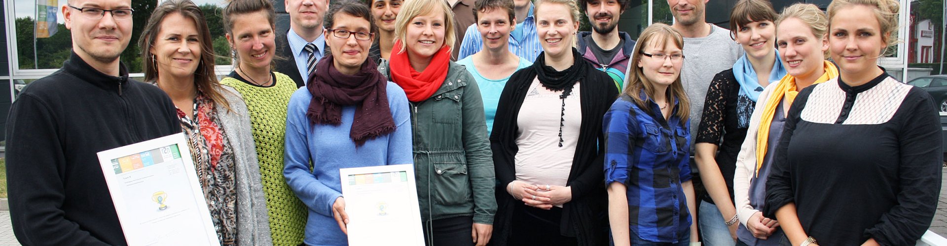 Gruppe aus Studierenden und Lehrenden, einge halten eine Urkunde in der Hand.