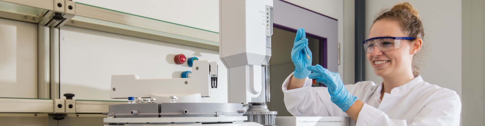 Studierende in Laborkittel hält eine Pipette in den Händen. Vor ihr ist Laboraapartur zu erkennen.