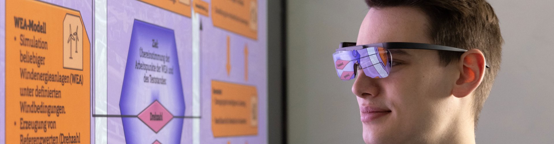 Junger Mann blickt auf eine Projektion, er trägt eine Eye-Tracking-Brille.