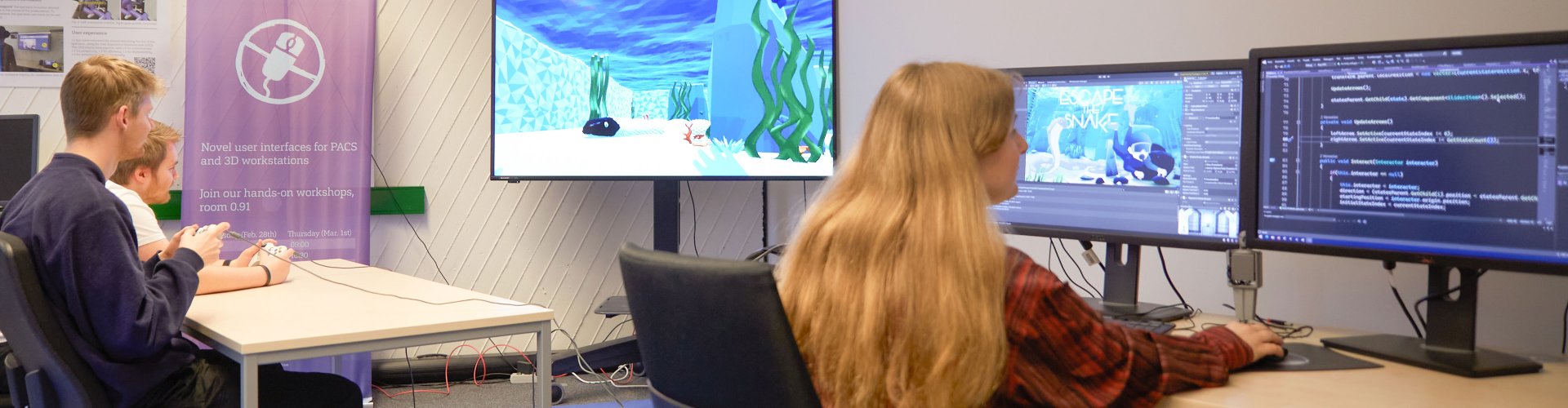 Studierende vor Rechnern und Bildschirmen an denen sie arbeiten. Auf den Bildschirmen ist eine animierte Unterwasserwelt zu sehen.