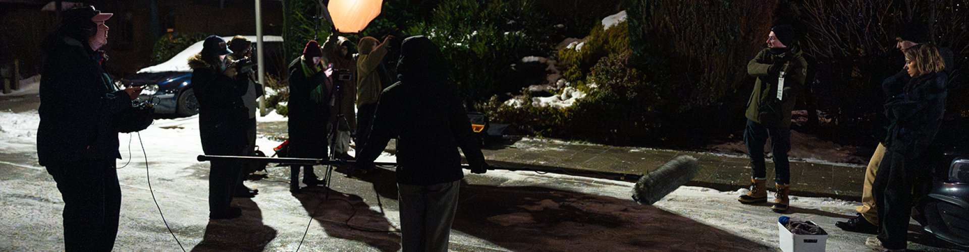 Eine Gruppe von Studierenden bei einem Filmdreh auf einer winterlich vereisten, dunklen Straße.