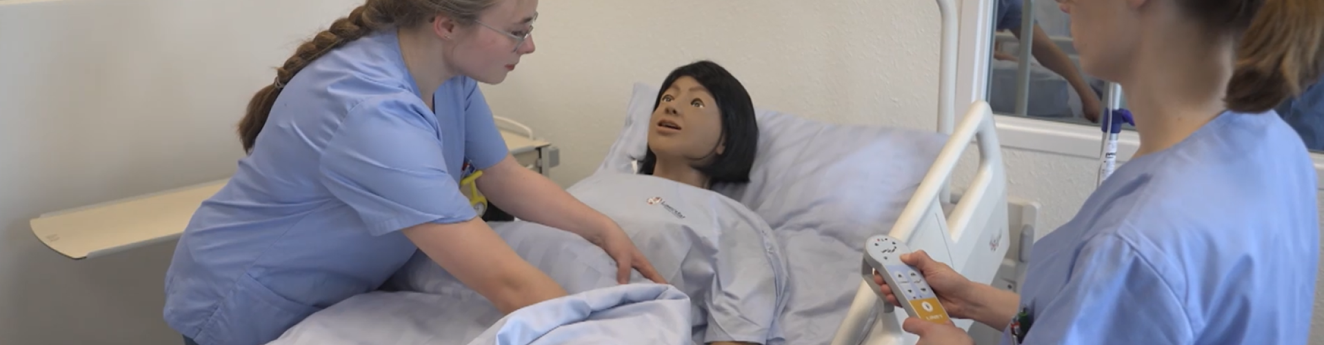 Zwei Pflegestudentinnen üben an einer lebensechten Puppe im Flensburger HealthLab eine Pflegesituation.