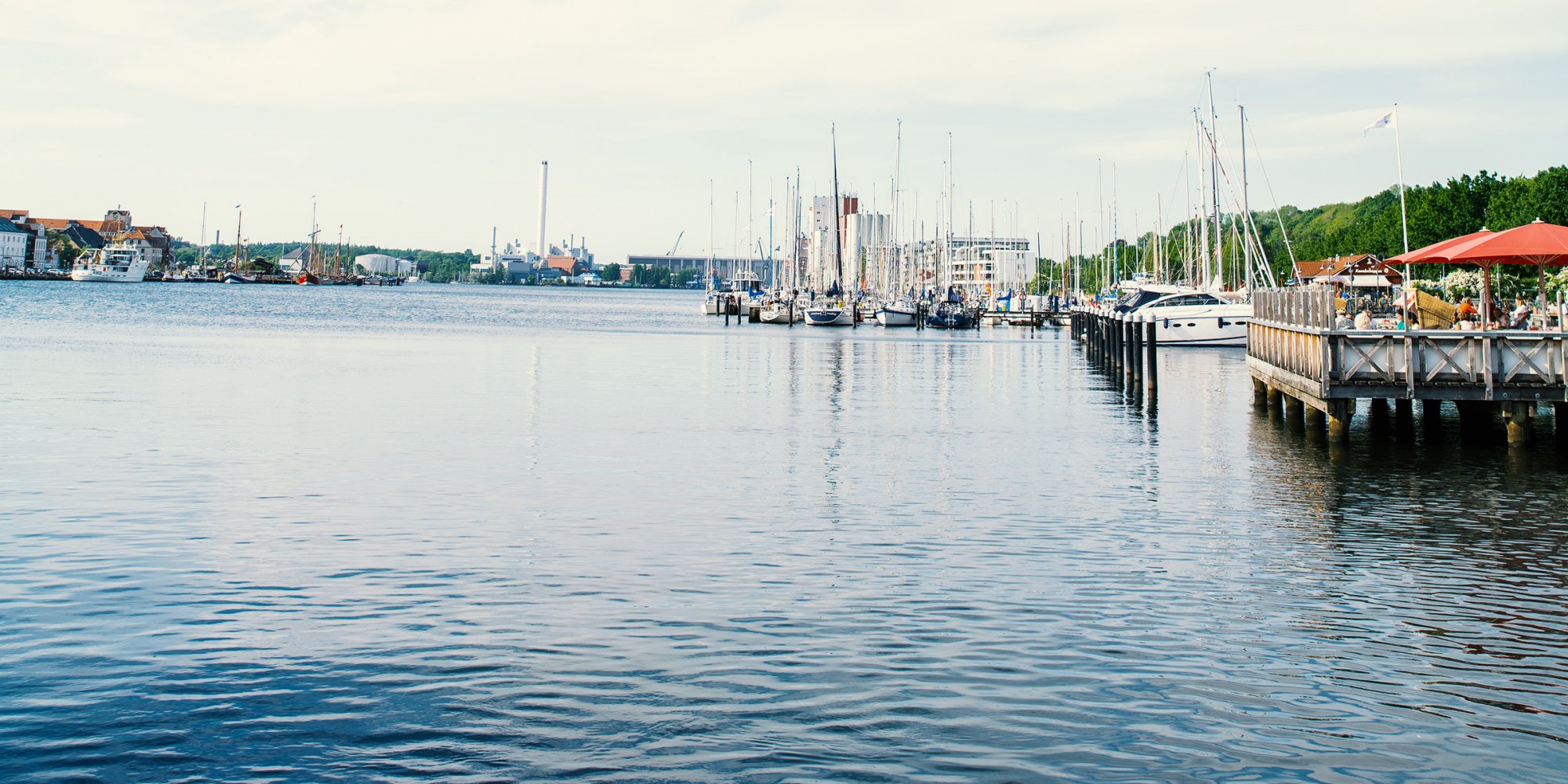 Blick auf das blaue Wasser im Hafen. rechts kleine Schiffe